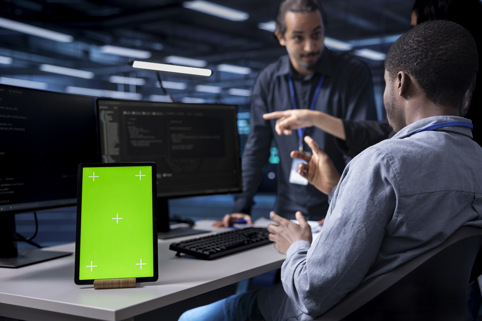 Multiethnic team using green screen tablet to oversee servers